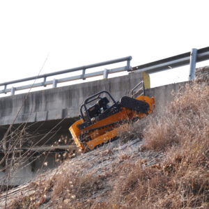 Remote control lawn mower working on a steep grassy slope